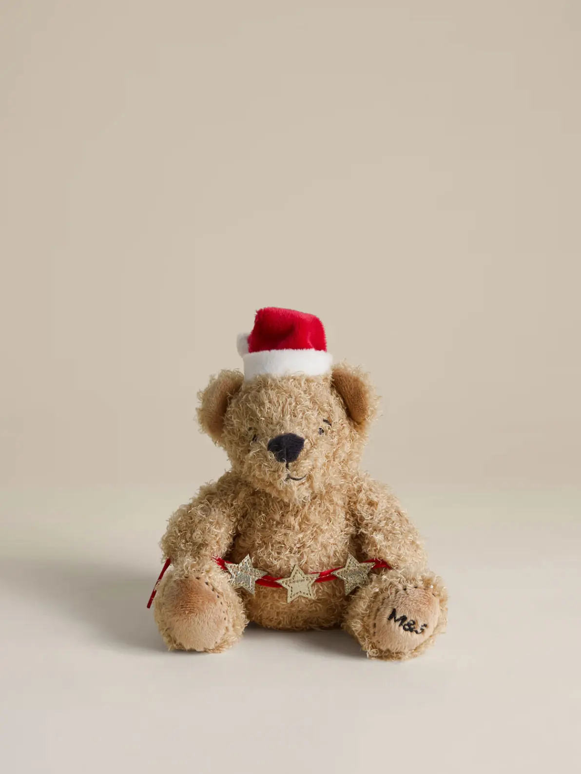 Image of a toy bear Christmas tree topper wearing a santa hat