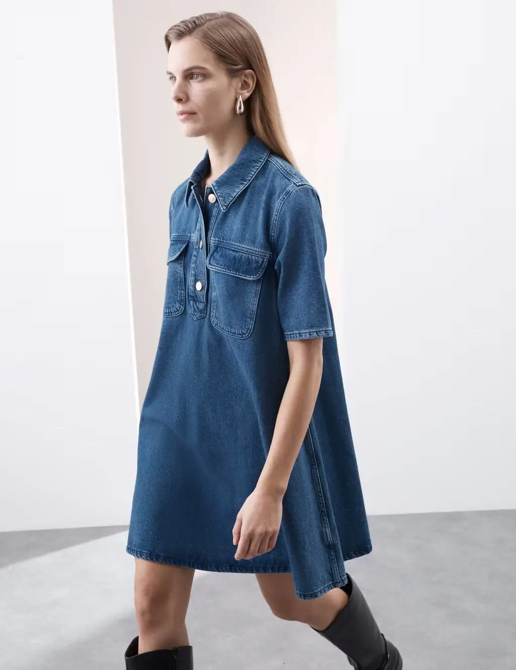 Woman wearing a short A-line denim shirt dress with knee high boots