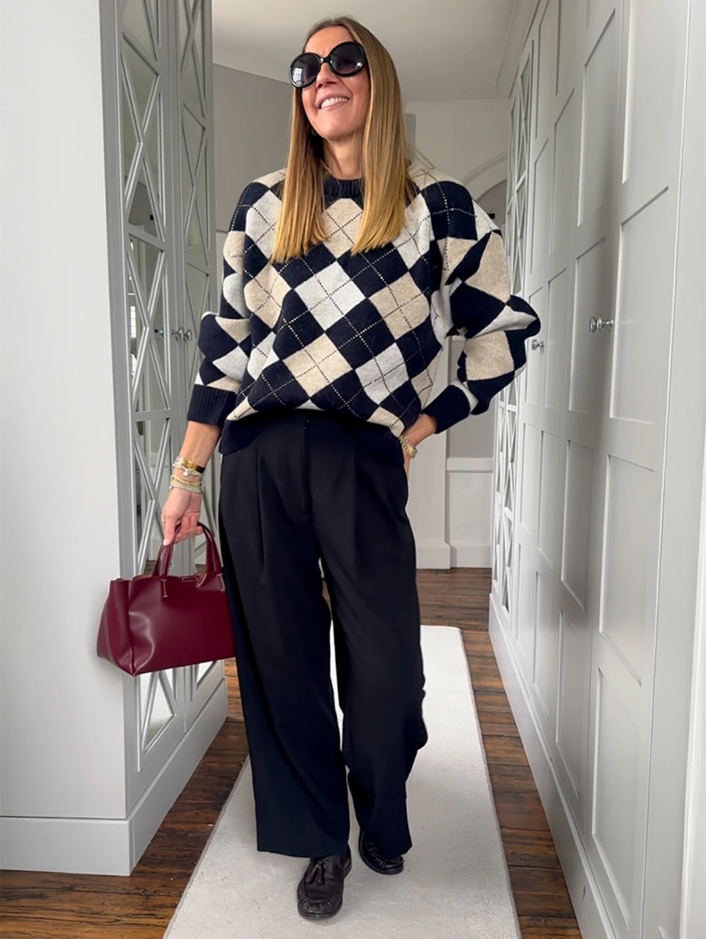 Hayley Karseras wearing an argyle jumper with black trousers and a burgundy bag