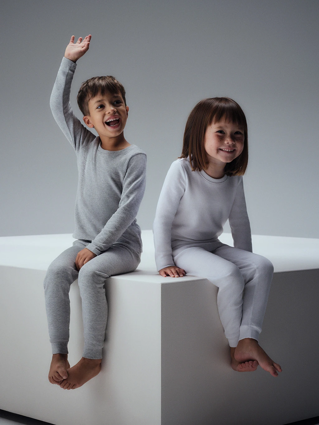 Two children in matching grey and white thermal sets.