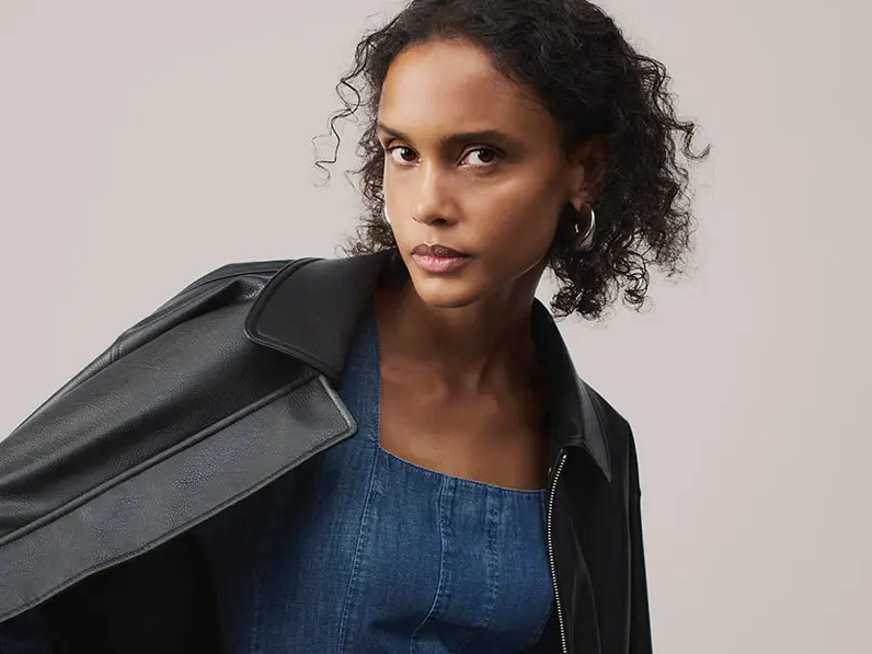 Woman wearing denim dress and black jacket at M&S