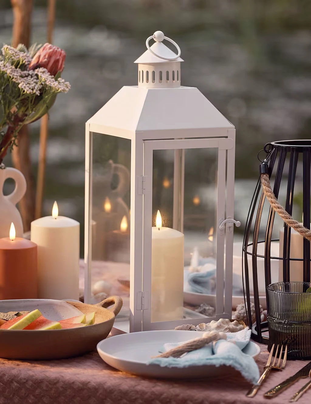 White hurricane lantern surrounded by pillar candles