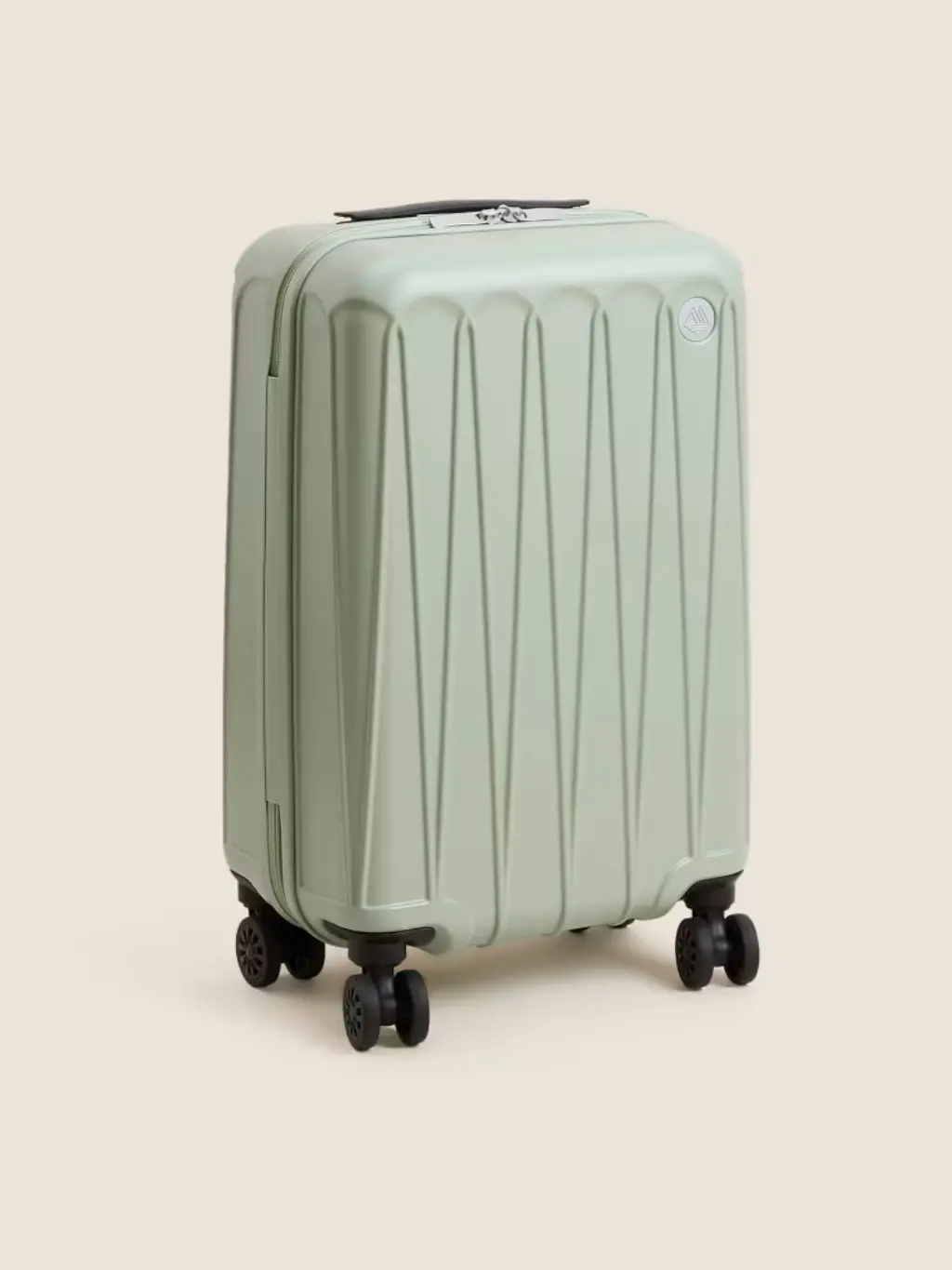 An image of a sage green hard sheel suitcase against a beige background