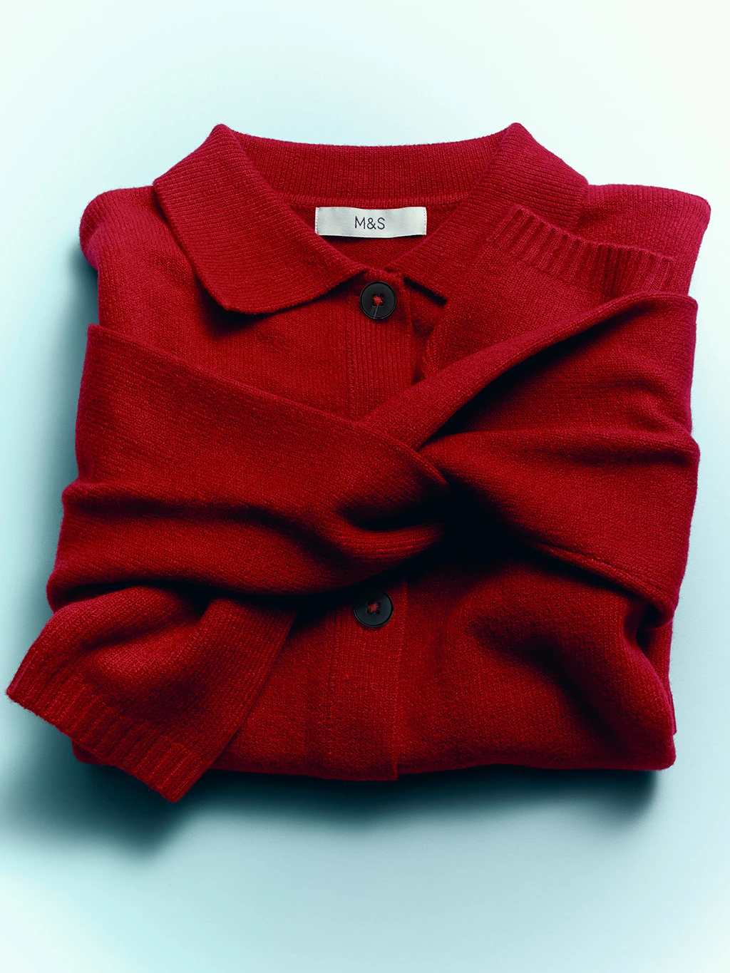 Red jumper folded with the sleeves tied in a knot.