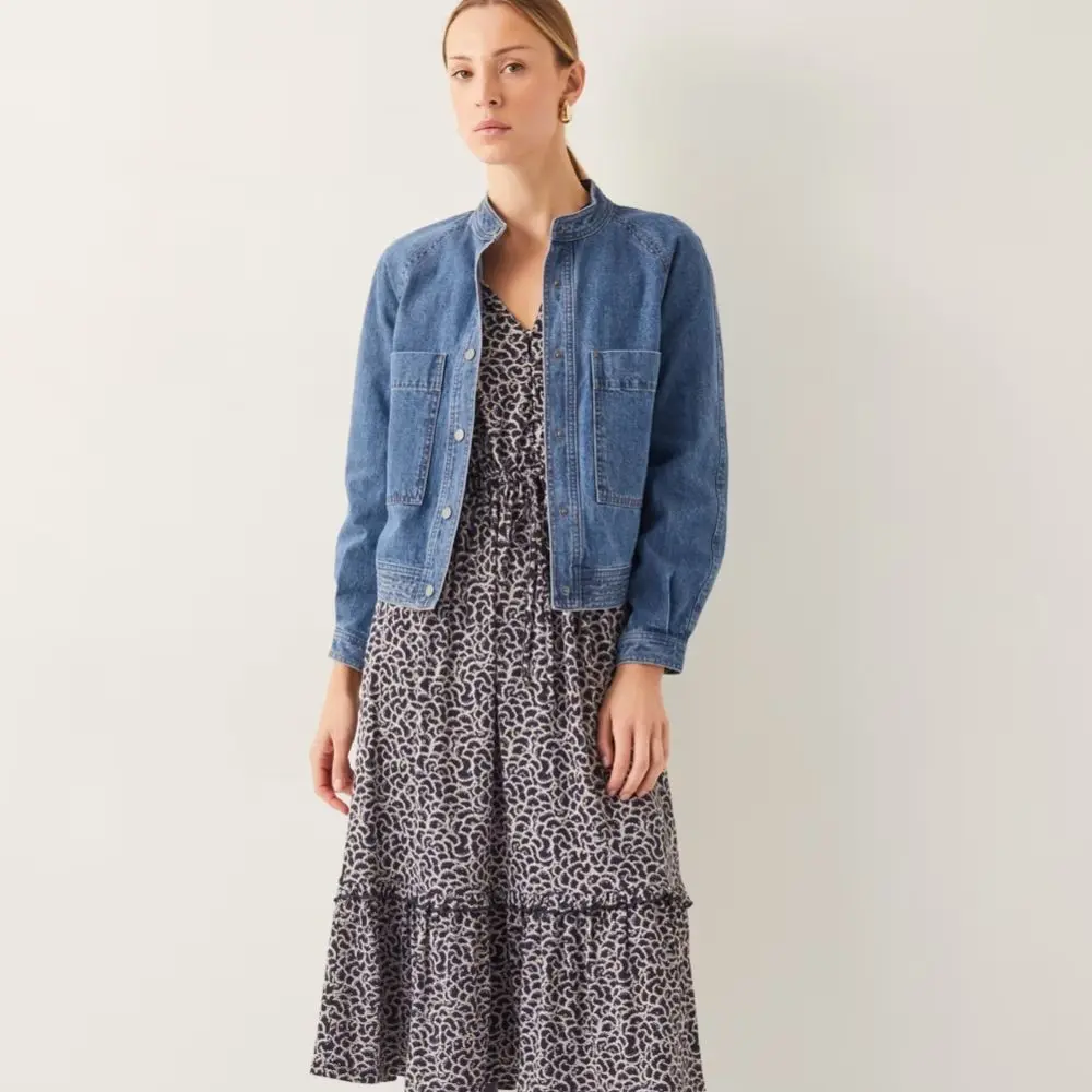 A model wears a printed midi dress and a denim jacket