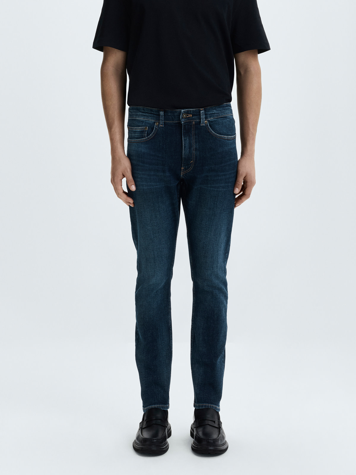 Man wearing dark slim fit jeans and a black T-shirt