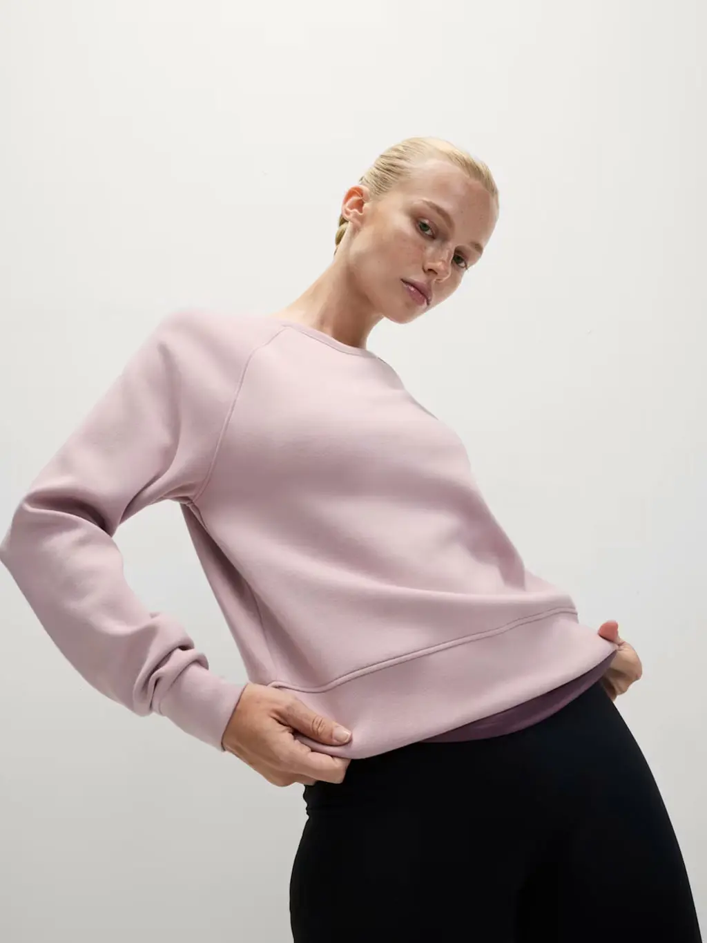 Woman wearing a pink sweatshirt with black leggings.