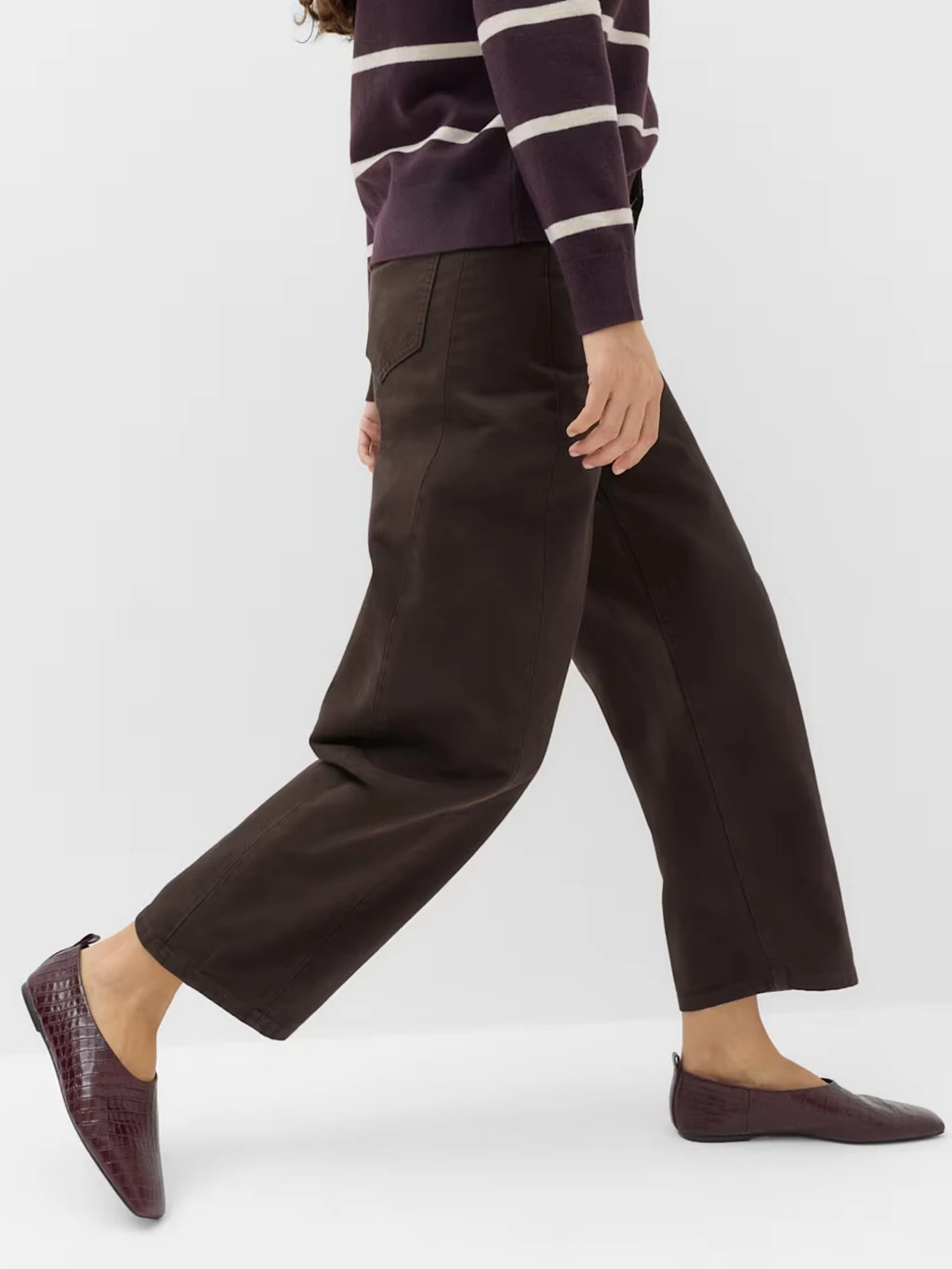 Close up of a model's legs wearing brown barrel trousers and leather ballet flats.