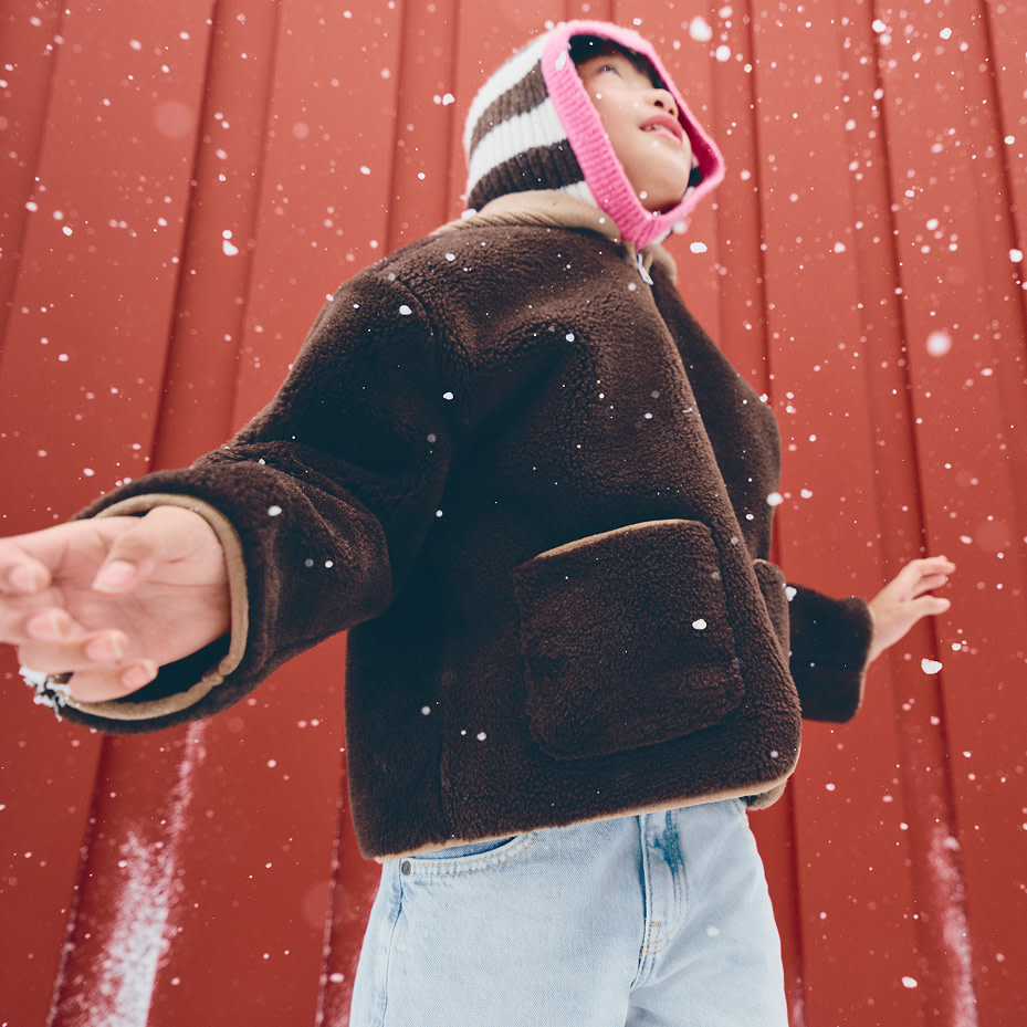 Boy wearing striped balaclava and brown jacket