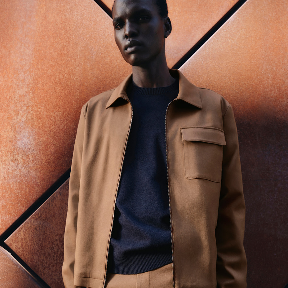 Man wearing brown jacket and navy jumper