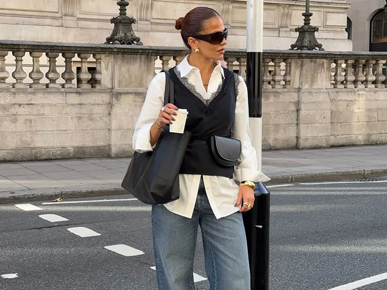 Woman in white top and jeans holding coffee cup