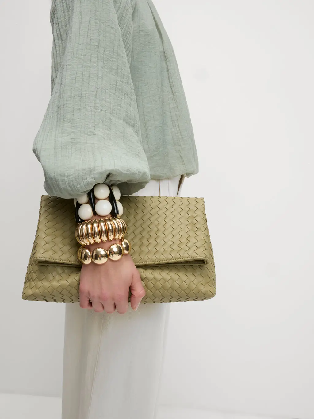 Woman holding olive green clutch bag under arm