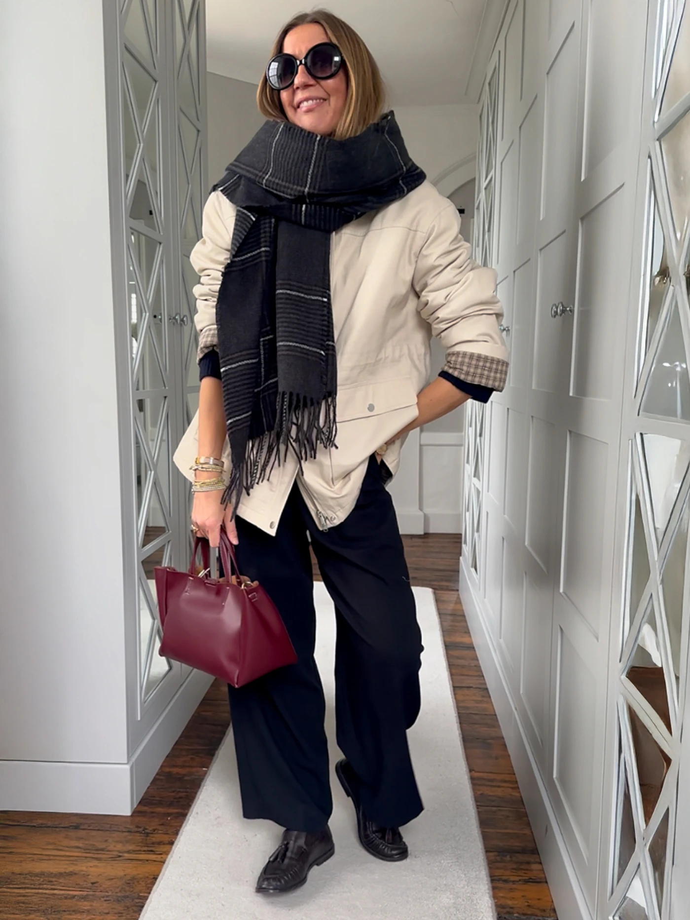 Hayley Karseras wearing a cream jacket, a checked scarf, black trousers and loafers