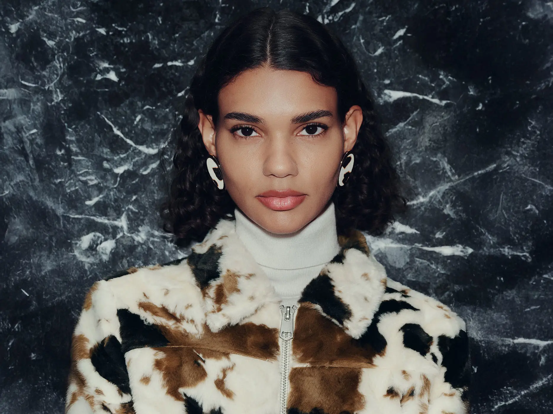 Woman wearing faux fur cow-print jacket