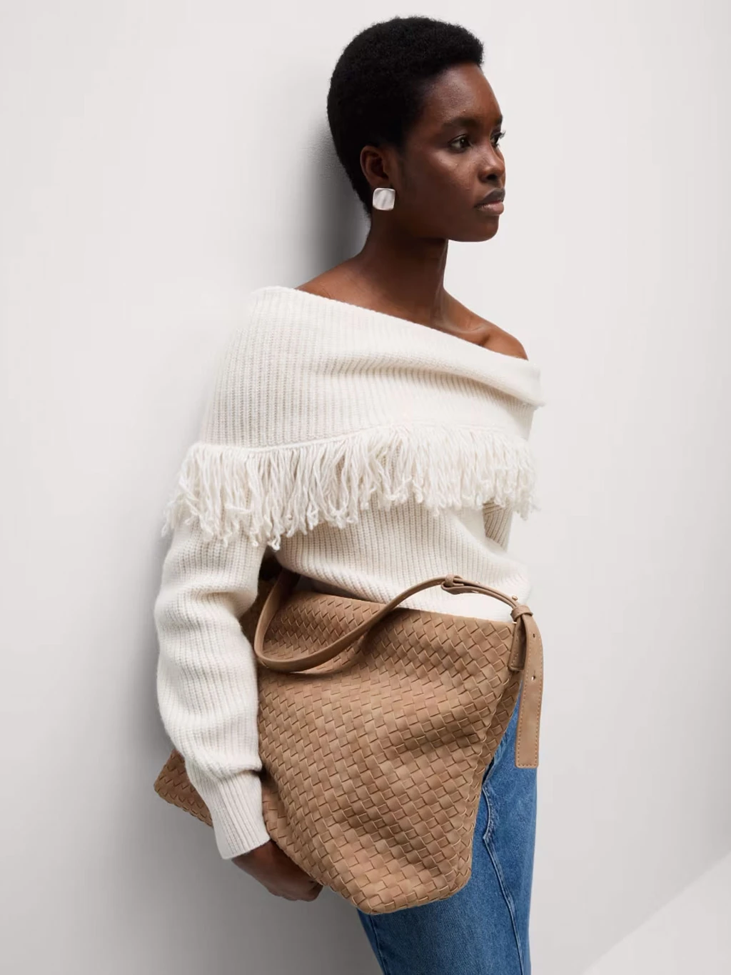 Woman wearing cream fringed off-the-shoulder jumper