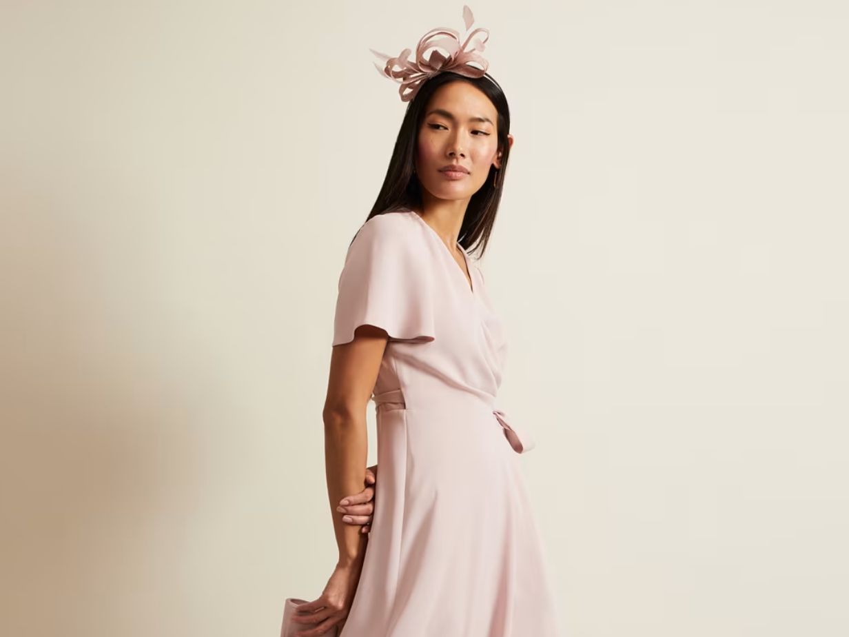 Woman wearing a pink dress and fascinator at M&S