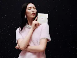 Woman wearing a pink jumper holding an M&S gift card