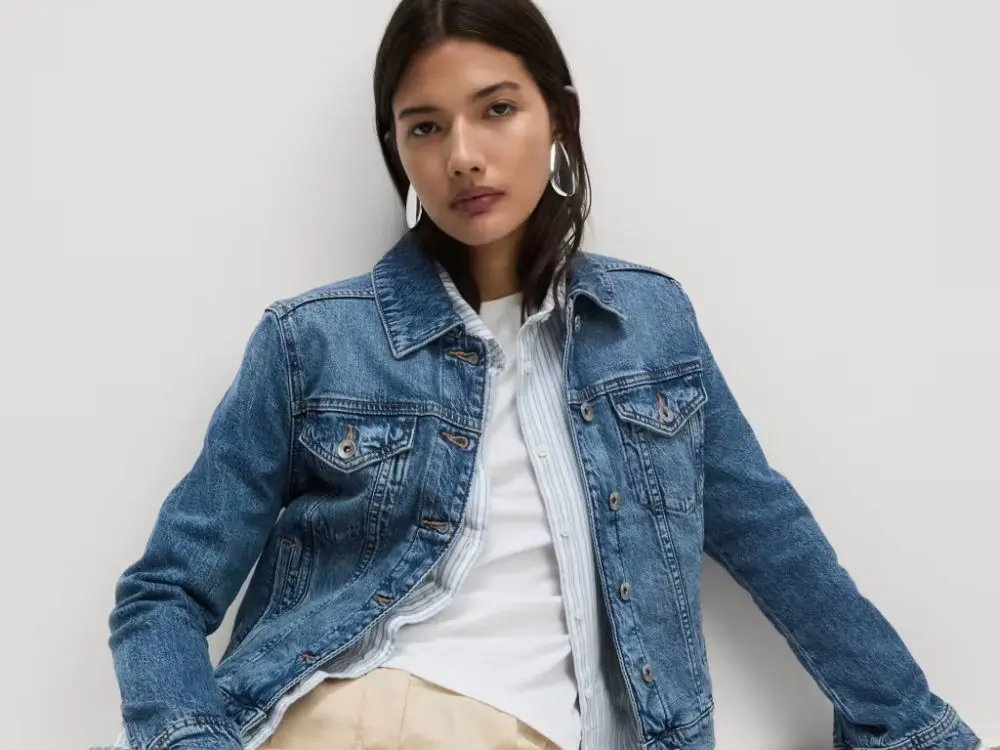 A woman wears a classic denim jacket over a stripe shirt and t-shirt
