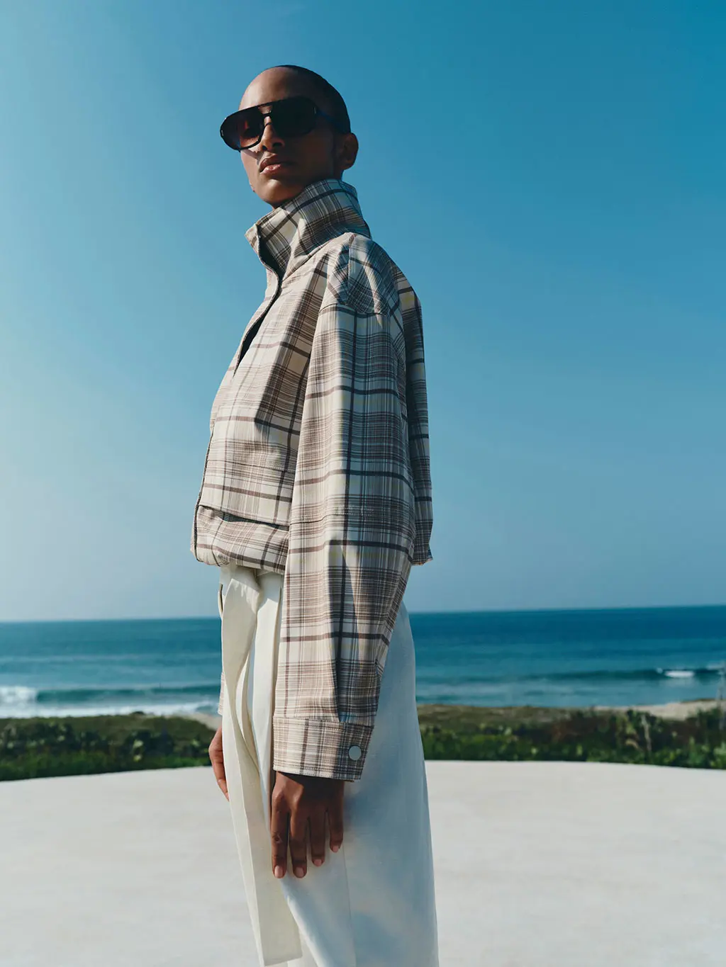 Woman wearing a checked bomber jacket with Bermuda shorts