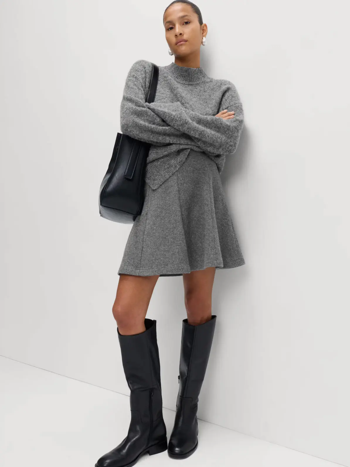Woman wearing grey high-neck jumper, matching grey mini skirt and black knee-high boots