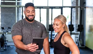 Two ISSA trainers smiling while reviewing workout results