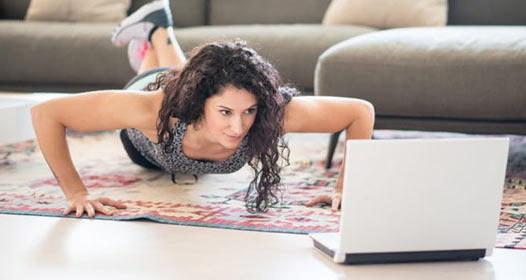 Woman doing pushups in front of a laptop