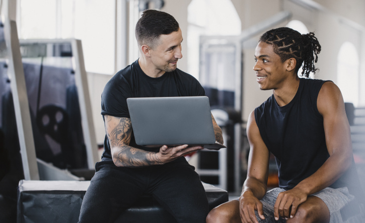 Trainer working with client using a laptop in a gym | ISSA