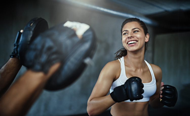 Woman hitting boxing pads with a trainer