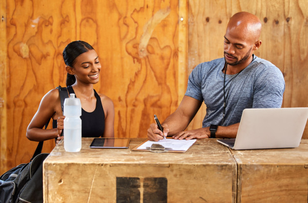 Shot of a young man and woman reading over a document in a gym stock photo