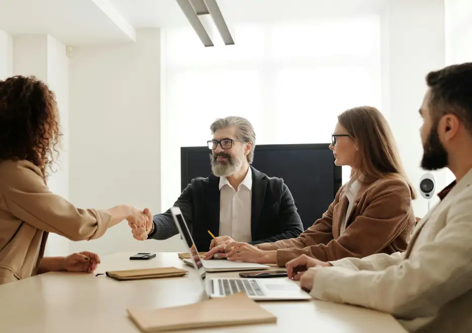 Professionals in a board meeting shaking hands