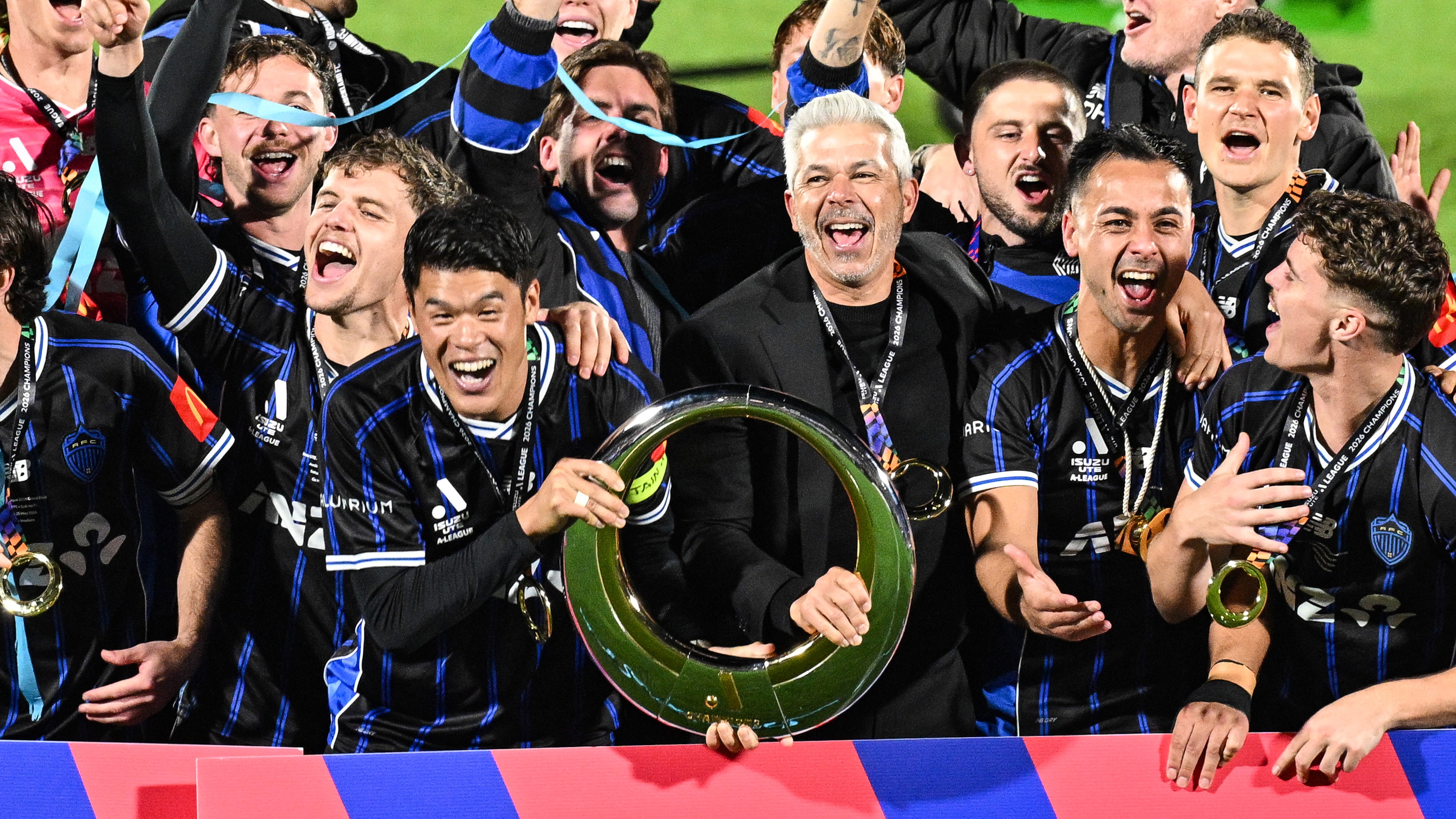 Auckland FC captain Hiroki Sakai and head coach Steve Corica celebrate with the A-League trophy