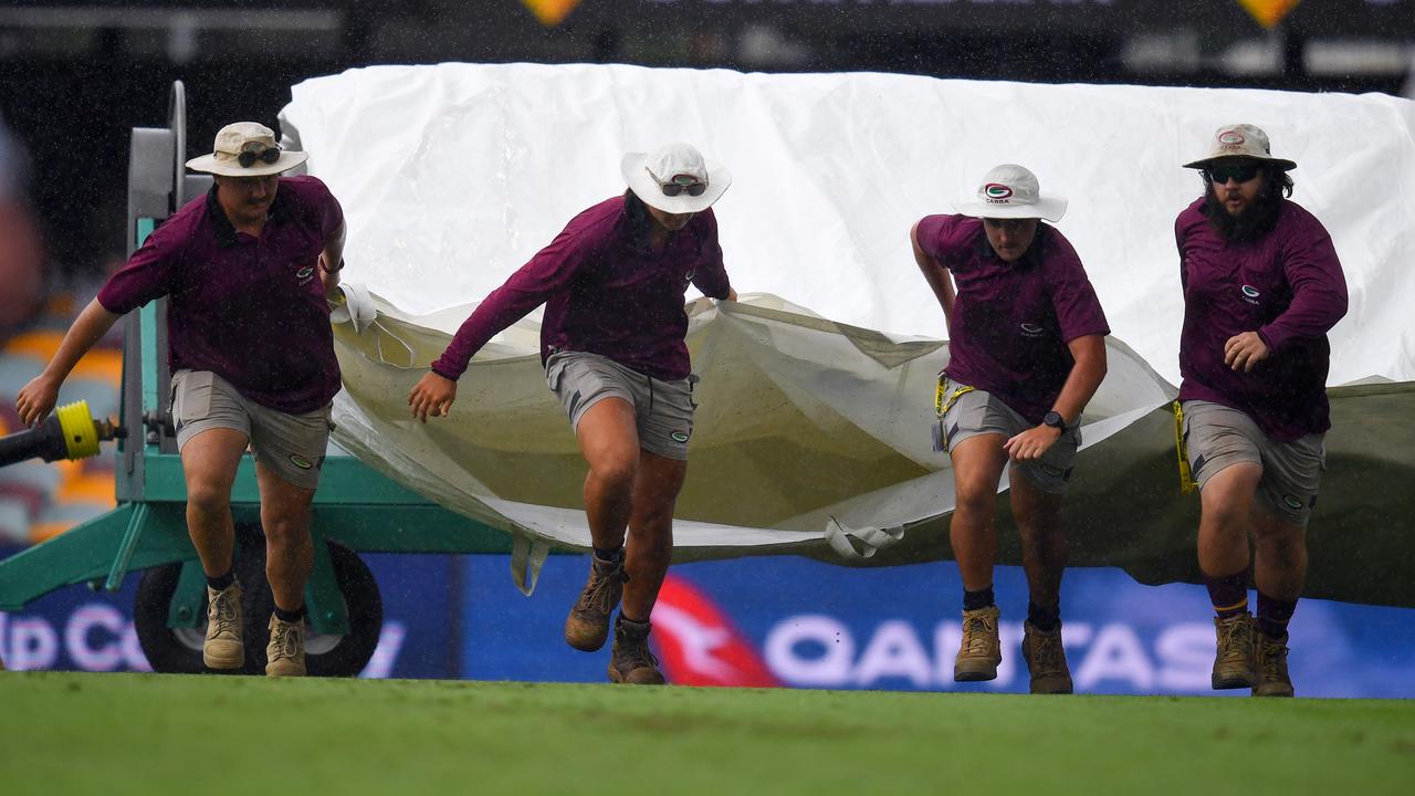 Ground staff rush to cover the wicket during a rain delay on the first day of the Brisbane Test