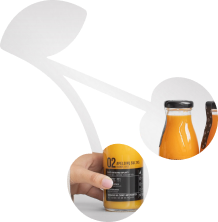 An image in a shape of a cherry inside of which a hand is grasping a glass bottle of orange juice.