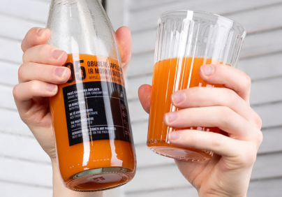 Hands holding bottle of apple orange and carrot juice