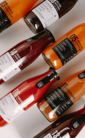 An image of glass bottles of juices and nectars laying diagonally in front of a white background 