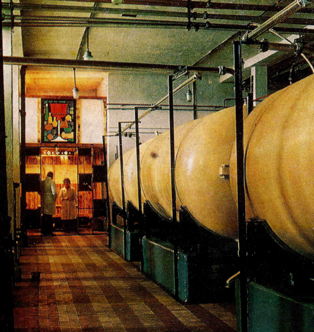 Archival photo from 1979 inside of a juice factory. Tanks and two people in white coats are visible.