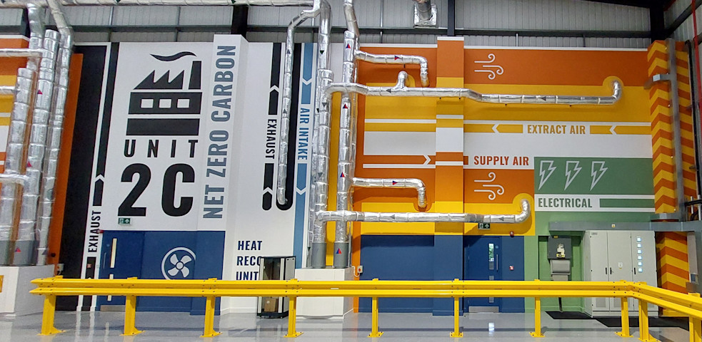 Interior wall of Medequip's South Normanton depot in Derbyshire, featuring a net zero carbon emissions display and integrated heat pump system.