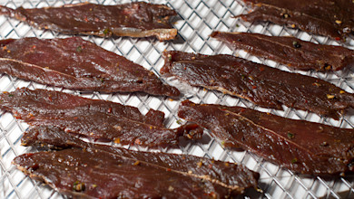 Wild-game jerky strips drying on a metal dehydrator rack