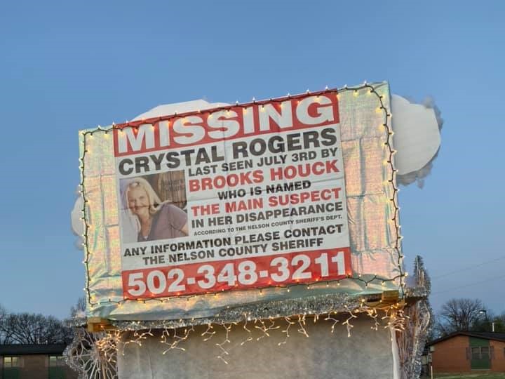 Billboard reading "MISSING CRYSTAL ROGERS. Last seen July 3rd by BROOKS HOUCK, the main suspect. Call 502-348-3211"