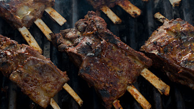 Grilled ribs with charred crust cooking on a hot grill