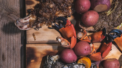 Redfish half-shell with crab claws, red potatoes and onion-butter on a wooden board