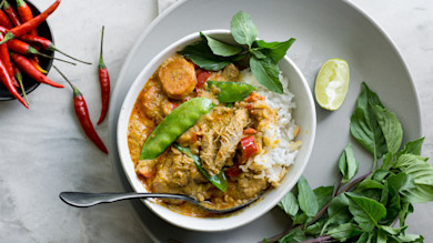 Panang pheasant curry with rice, snow peas, Thai basil and lime wedge in a bowl
