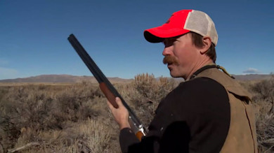 Ryan Callaghan holding double-barrel shotgun in sagebrush under blue sky
