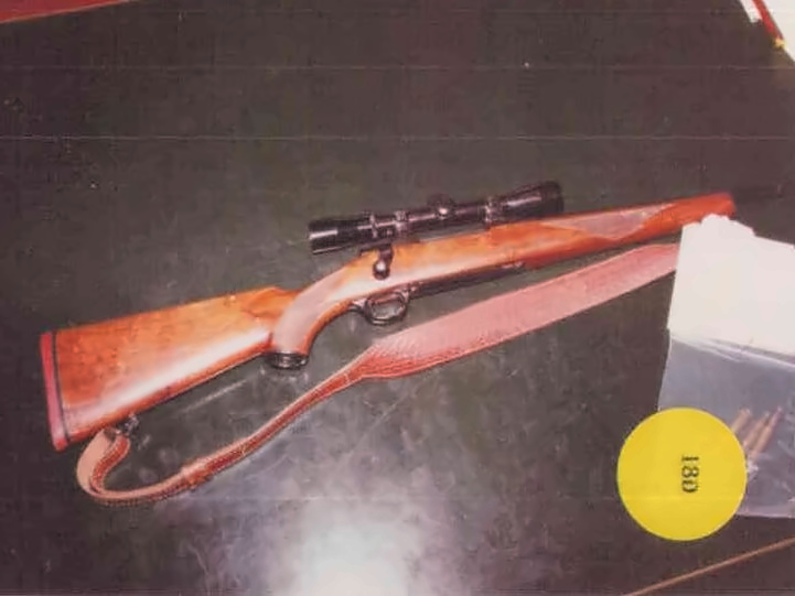 Bolt-action rifle with wooden stock and scope, leather sling; ammo box labeled 18D