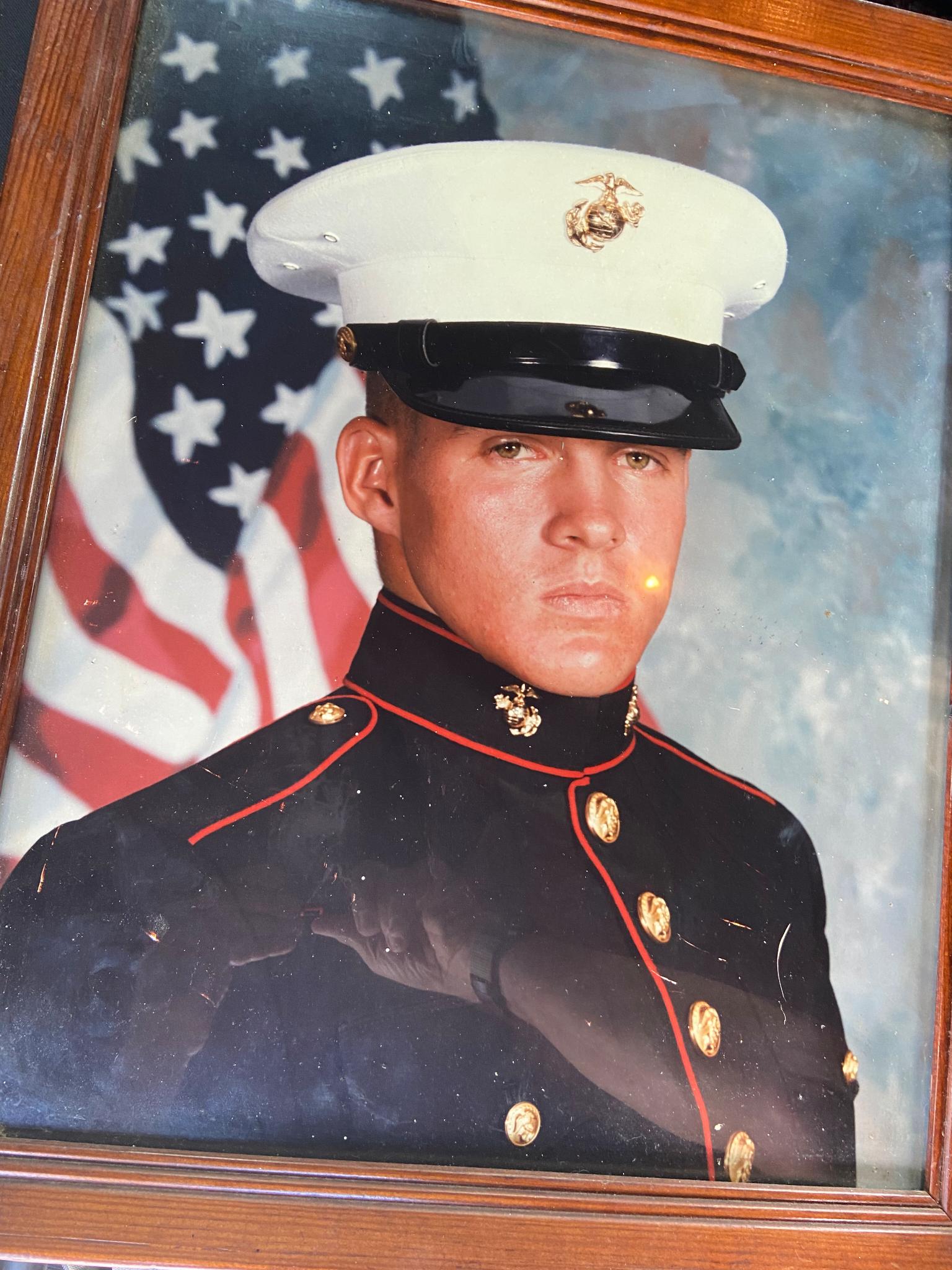 Marine in dress blues and white cap before an American flag, framed portrait