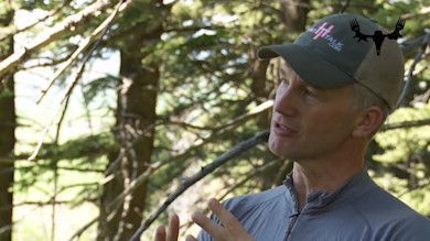 Hunter speaking and gesturing in a forest with MeatEater antler logo overlay