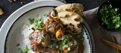 Indian-spiced antelope osso buco on rice, topped with cilantro, served with charred naan