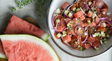 Greek watermelon salad in bowl with feta, cherry tomatoes, cucumber and red onion
