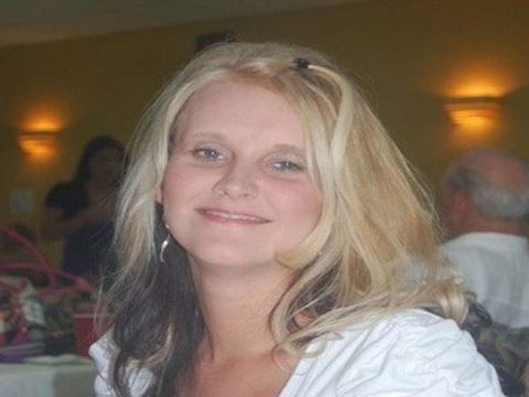 Smiling blonde woman wearing white top at indoor social gathering