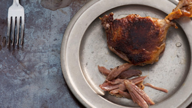 Goose leg confit and shredded meat on a pewter plate, fork at left